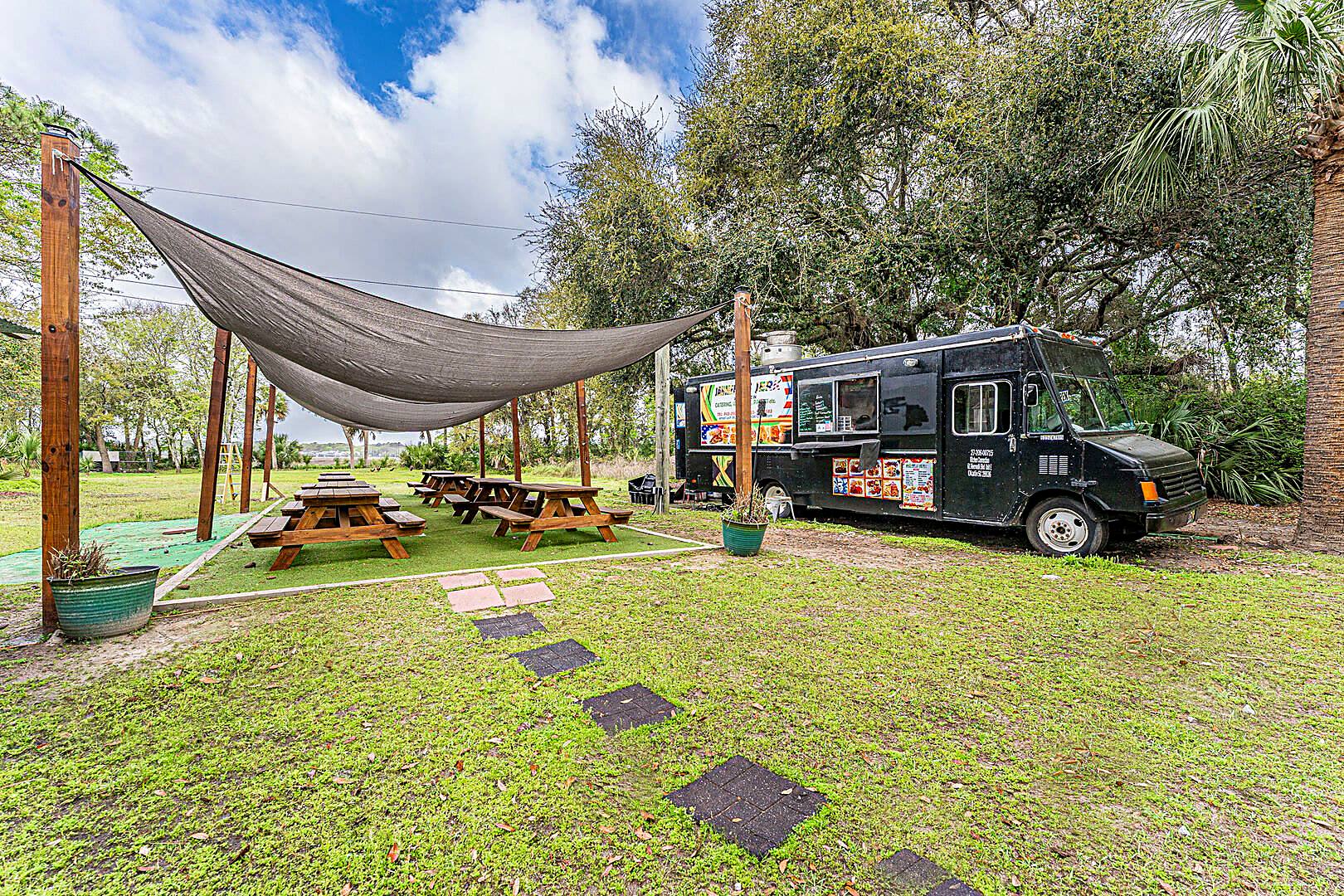 Food truck and picnic tables under a shade sail at the Barnacle Bill's food truck park, Hilton Head Island